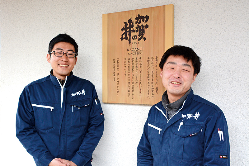 完成した酒蔵の看板の前で笑顔の二人